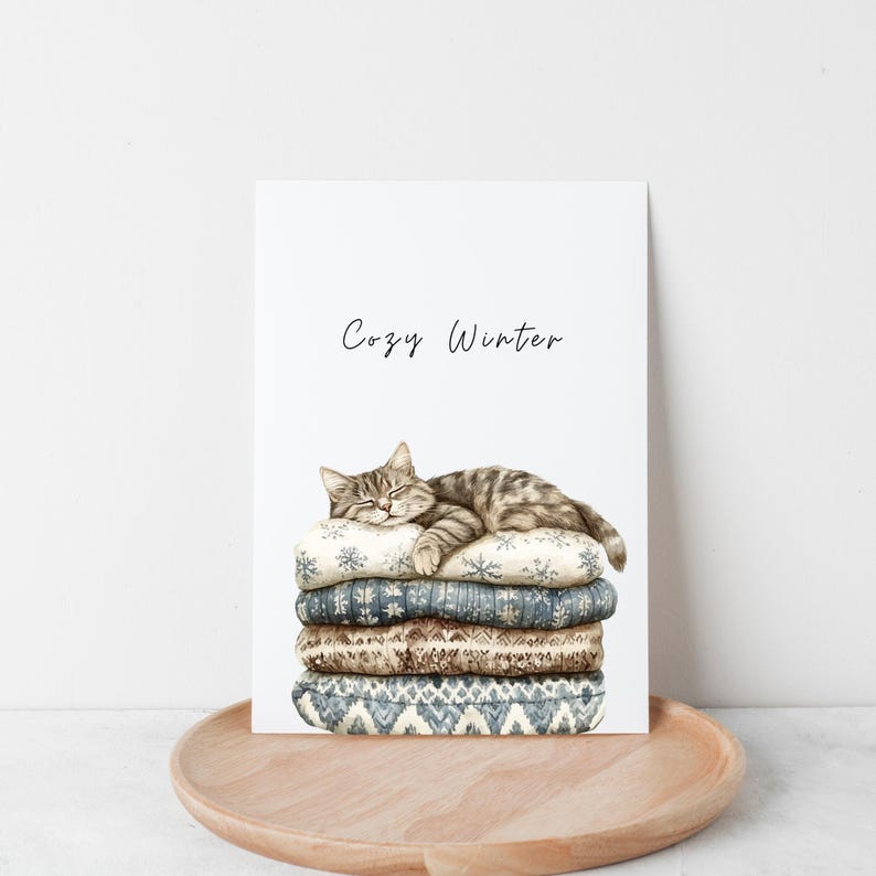 May include: A watercolor illustration of a cat sleeping on a stack of cozy blankets with the text "Cozy Winter" above the cat.