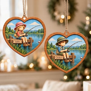 May include: Two heart-shaped wooden ornaments hanging by twine. One features a girl fishing with the name Sophia on a dock sign. The other shows a boy fishing with the name Jackson on a dock sign. Both depict a lake, trees, and blue sky.