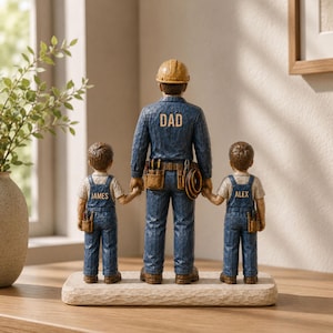 May include: A wooden figurine depicting a father figure in a blue work uniform with the word "DAD" on the back, holding hands with two children in overalls. The children's names, "JAMES" and "ALEX", are on their shirts.