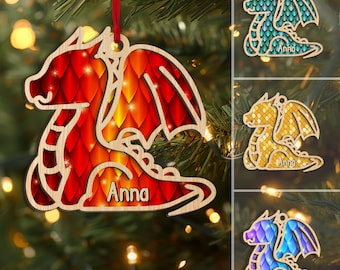 May include: Wooden dragon Christmas ornament with a red ribbon. The dragon has a red and orange scale pattern with the name "Anna" on it. Additional dragon ornaments in teal, gold, and purple are also shown.