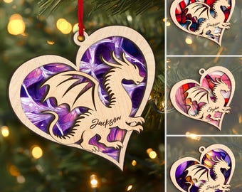 May include: A wooden heart-shaped Christmas ornament with a cutout of a dragon. The dragon is in a purple and pink swirl pattern. The ornament is personalized with the name "Jackson".