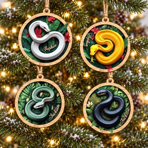 May include: Four circular wooden ornaments featuring coiled snakes in white, yellow, green, and black. Each ornament displays a snake resting on green leaves with red or white flowers. The names Sophia and Jackson are printed on the ornaments.
