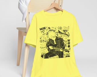 Könnte beinhalten: Gelbes T-Shirt mit einem schwarz-weißen Grafikdruck einer Person, die Gitarre spielt. Die Grafik enthält den Text "MUSE", "BE MINE", "Closer Than This", "Roberts Tower", "SLOW DANCE", "INTERLUDE SHOWTIME", "EMERALD GARDEN", "WHO" und "JIMIN".
