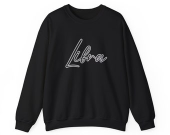 Op de afbeelding: Zwart sweatshirt met een witte omtrek van het woord "Libra" in een cursief schrift.