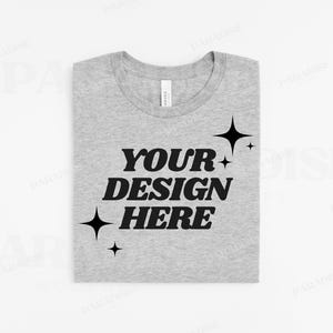 May include: A heather grey t-shirt with the text "YOUR DESIGN HERE" in black, surrounded by small star shapes.