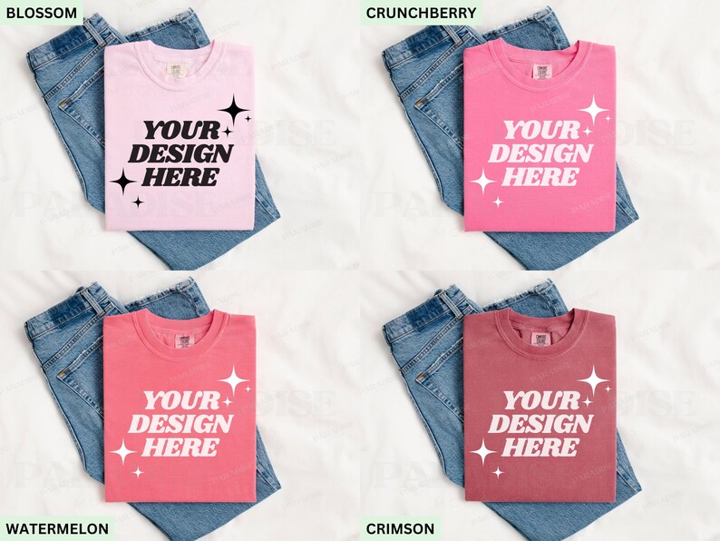 May include: Four t-shirts in shades of pink and red, each with the text "YOUR DESIGN HERE". The shirts are folded on top of blue denim jeans. The colors are: light pink, bright pink, coral, and maroon.