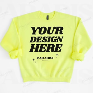 May include: A neon yellow sweatshirt with the text "YOUR DESIGN HERE" in bold black letters. Below the text is "PARADISE MOCKUPS" and star graphics. The sweatshirt has a crew neck and long sleeves with rolled cuffs.