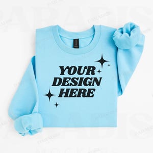 May include: A light blue sweatshirt with the text "YOUR DESIGN HERE" in black lettering and a few small stars.