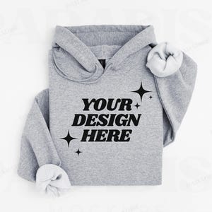 May include: A gray hoodie with the text "YOUR DESIGN HERE" in black lettering. The hoodie has a drawstring hood and a relaxed fit.