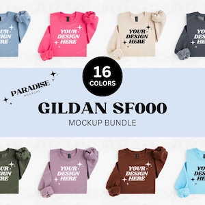 Pode incluir: Pacote de maquetes de 16 sweatshirts Gildan SF000 em várias cores. As sweatshirts estão dispostas sobre uma superfície branca e apresentam o texto "YOUR DESIGN HERE" impresso na parte frontal.