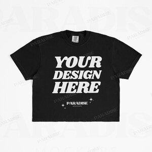 May include: Black t-shirt featuring the white text "YOUR DESIGN HERE". Below the text is "PARADISE MOCKUPS" and two star graphics. The t-shirt has a crew neck design.