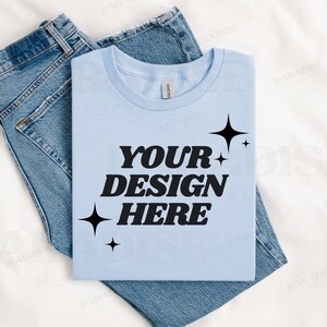 May include: A light blue t-shirt with the text "YOUR DESIGN HERE" in black, surrounded by small black stars.