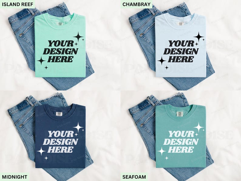 May include: Four t-shirts in various colours: Island Reef, Chambray, Midnight, and Seafoam. Each shirt displays the text "YOUR DESIGN HERE" in white, with starburst graphics. The shirts are folded on top of blue denim jeans.