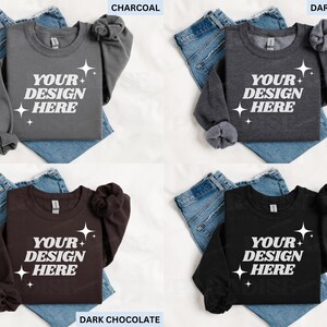 May include: Four sweatshirts in charcoal, dark heather, dark chocolate, and black, each with the text "YOUR DESIGN HERE" and starburst graphics. The sweatshirts are displayed on top of blue jeans.