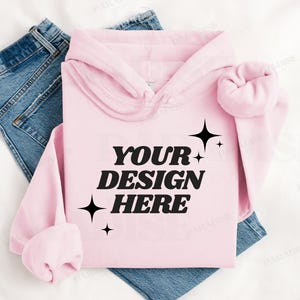 May include: A pink hoodie with a black graphic that says "YOUR DESIGN HERE" with stars around the text.