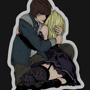 May include: A sticker depicting an anime-style illustration of two figures in an embrace. One figure has brown hair and wears a dark blue jacket over a white shirt. The other has blonde hair and wears a black dress and lace stockings.
