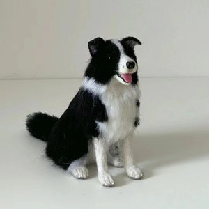 May include: A needle felted black and white border collie dog figurine. The dog is sitting with its tongue sticking out and looking to the right.