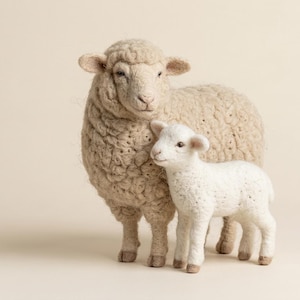 May include: A handcrafted wool sheep and lamb figurine. The adult sheep is a light beige color, and the lamb is white. The sheep stands next to the lamb, both with detailed wool textures. The background is a soft, neutral tone.