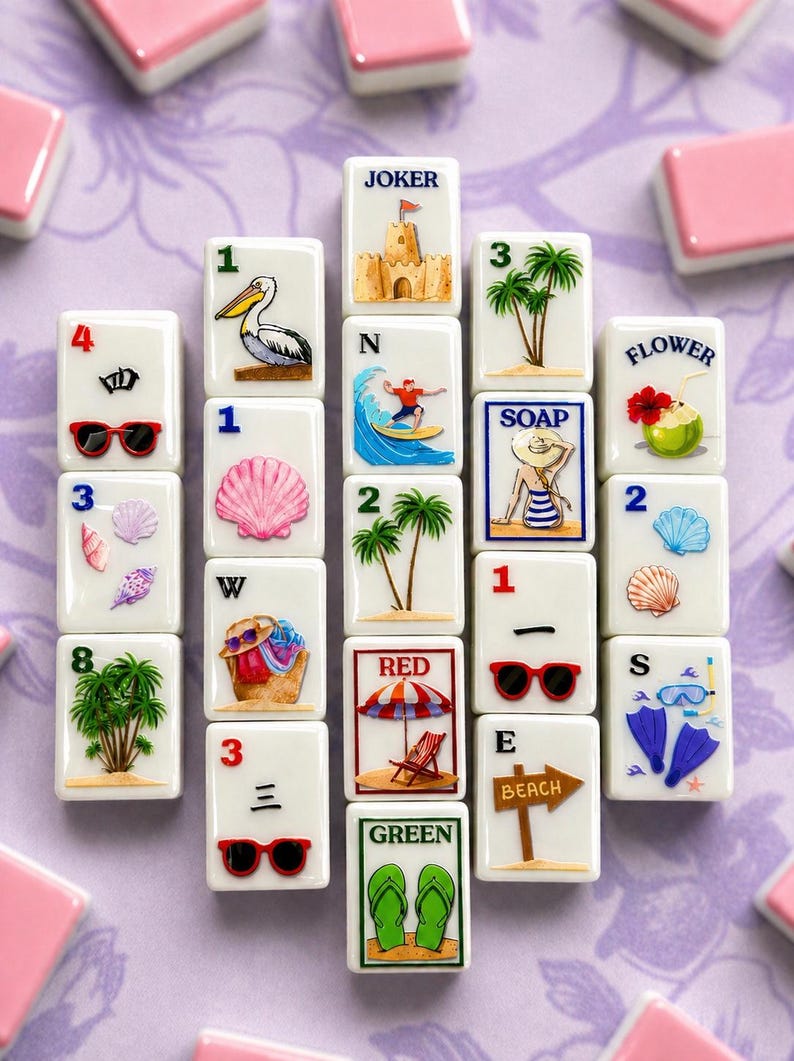 May include: A collection of white mahjong tiles with beach-themed illustrations, including a pelican, palm trees, sunglasses, and a sandcastle. The tiles are arranged on a purple surface, with pink tiles in the background.