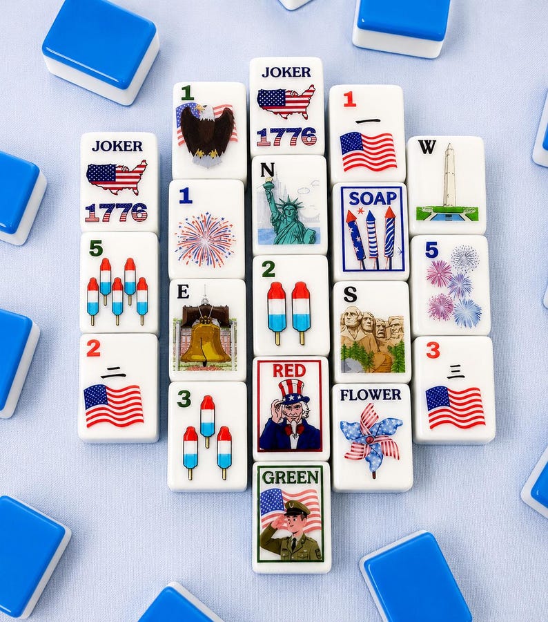 May include: A collection of white Mahjong tiles with patriotic designs and text. Tiles feature images of the American flag, the Statue of Liberty, fireworks, and Uncle Sam. The set includes blue and white tiles.