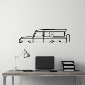 May include: A black metal outline of a Land Rover Defender mounted on a white wall above a desk with a lamp, a laptop, and a black stool.