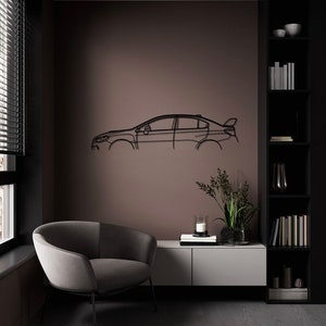 May include: A black metal car outline wall art. The artwork is mounted on a brown wall in a modern living room. The room features a grey armchair, a white and grey cabinet, and a black bookshelf.