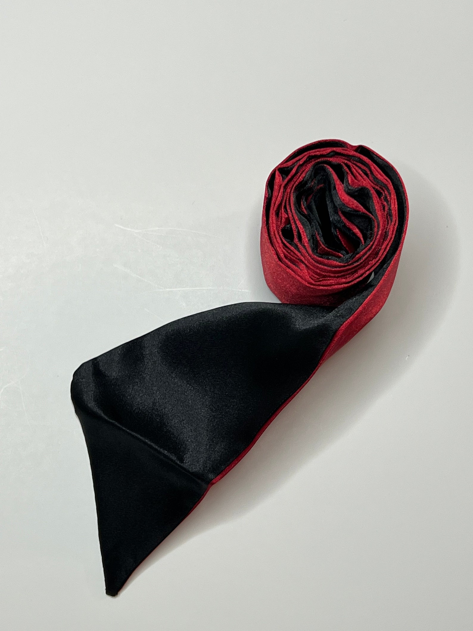 Red and black silk BDSM blindfold rolled up for bondage restraints and sensory play