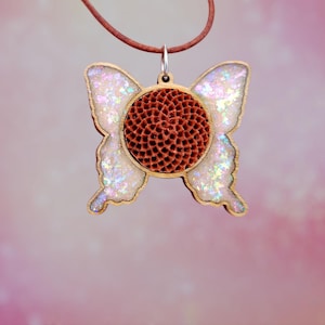 May include: A wooden butterfly pendant necklace with a brown, textured center and iridescent glitter wings.