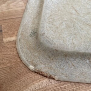 May include: A close-up of a light green, rectangular,  tray made of a material that resembles fiberglass. The tray has a slightly rounded edge and shows signs of wear and tear.