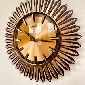 May include: A gold and black sunburst clock with the word "Gigant" on the face.