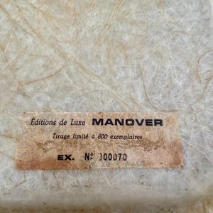 May include: A close-up of a white label with the text "Editions de Luxe MANOVER Tirage limit&eacute; &agrave; 800 exemplaires EX. N&deg; 00070" printed on it.
