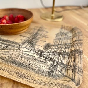 May include: A rectangular tray with a beige background and a black and white line drawing of a city scene. The tray has a wood-grain texture.