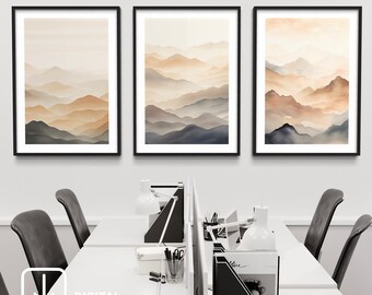 Puede incluir: Tres impresiones enmarcadas de una pintura de acuarela de una cordillera con un efecto brumoso y brumoso. Las montañas son en tonos de marrón, naranja y azul. Las impresiones están colgadas en una pared blanca en un entorno de oficina moderno.