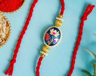 Handgemaakte Meenakari Lotus Rakhi, traditionele blauw geëmailleerde rakhi voor broer, designer bloemenrakhi met gouden kralen en rood gevlochten draad