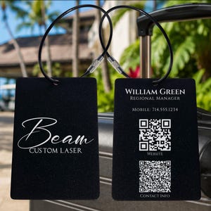 May include: Two rectangular black luggage tags with black wire loops. One tag displays the text Beam CUSTOM LASER. The other tag features the text WILLIAM GREEN, REGIONAL MANAGER, MOBILE: 714.555.1234, two QR codes labeled WEBSITE and CONTACT INFO.