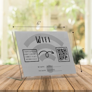 May include: A clear acrylic WiFi sign, 6 inches wide and 4 inches tall, with the word "WIFI" and a QR code. The sign includes instructions to scan with a phone's camera to connect automatically. The network name and password are also displayed.