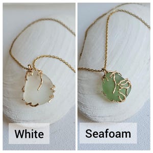 K&ouml;nnte beinhalten: Zwei Halsketten mit goldenen Ketten und Anh&auml;nger aus Meerschaum. Der Anh&auml;nger links ist aus wei&szlig;em Meerschaum und der Anh&auml;nger rechts aus gr&uuml;nem Meerschaum. Die Anh&auml;nger sind beide von einem goldenen Drahtdesign umgeben. Die Halsketten sind mit "Wei&szlig;" und "Meerschaum" beschriftet.