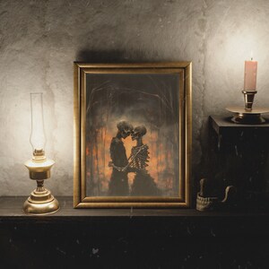 May include: A framed artwork depicting two skeletons embracing in a dark forest setting. The artwork is displayed on a wooden shelf with a lit oil lamp and a candle on either side.