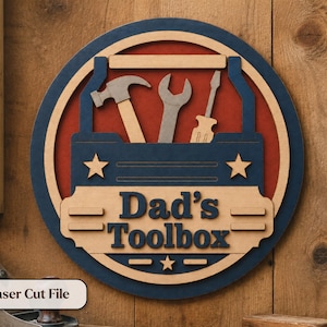 May include: A round wooden sign with a blue and red toolbox design. The sign features a hammer, wrench, and screwdriver, with the text "Dad's Toolbox" and the words "Laser Cut File".