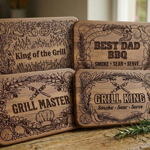 May include: Four wooden cutting boards with engraved text and decorative borders. The boards feature phrases like "King of the Grill," "Best Dad BBQ," "Grill Master," and "Grill King." Each board has a unique design with grilling-related imagery.