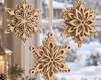 May include: Three hanging snowflake ornaments crafted from light-coloured wood, each featuring intricate laser-cut geometric patterns and layered designs. Each ornament is suspended by a simple cream-coloured ribbon loop for display.
