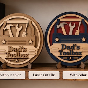 May include: Two circular wooden signs featuring a laser-cut toolbox design with a hammer, wrench, and screwdriver. One sign is natural wood, while the other features blue and red accents. Both signs display the text "Dad's Toolbox" and stars.