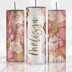 K&ouml;nnte beinhalten: Drei Edelstahlbecher mit einem rosa-goldenen Blumendesign. Der mittlere Becher tr&auml;gt den Namen "Melissa" in goldenen Glitzer.
