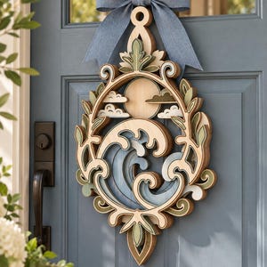 May include: A layered wooden wall hanging featuring a circular design with a sun, clouds, and ocean waves. The piece is framed by decorative scrollwork and foliage in shades of light wood, sage green, and blue, topped with a blue fabric bow.
