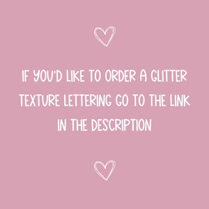 May include: Pink background with white text that reads "IF YOU'D LIKE TO ORDER A GLITTER TEXTURE LETTERING GO TO THE LINK IN THE DESCRIPTION". There are two white hearts at the top and bottom of the text.