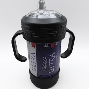 Pode incluir: Uma mamadeira preta e transparente com uma al&ccedil;a preta e uma base preta. A mamadeira foi projetada para conter uma lata de cerveja Michelob Ultra. A lata &eacute; vis&iacute;vel atrav&eacute;s da mamadeira e apresenta as palavras "ULTRA" e "Michelob Ultra" em branco.