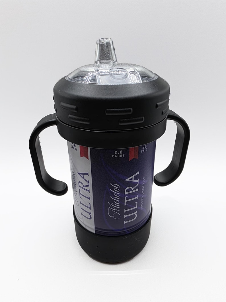 Pode incluir: Uma mamadeira preta e transparente com uma al&ccedil;a preta e uma base preta. A mamadeira foi projetada para conter uma lata de cerveja Michelob Ultra. A lata &eacute; vis&iacute;vel atrav&eacute;s da mamadeira e apresenta as palavras "ULTRA" e "Michelob Ultra" em branco.