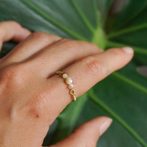 Può includere: Un anello d'oro con una fila di piccole perle rotonde bianche.