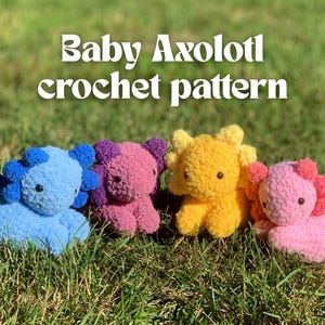 May include: Four colorful, crocheted axolotl toys in blue, purple, yellow, and pink, sitting on green grass. The text "Baby Axolotl crochet pattern" is displayed in white, stylized font above the toys.