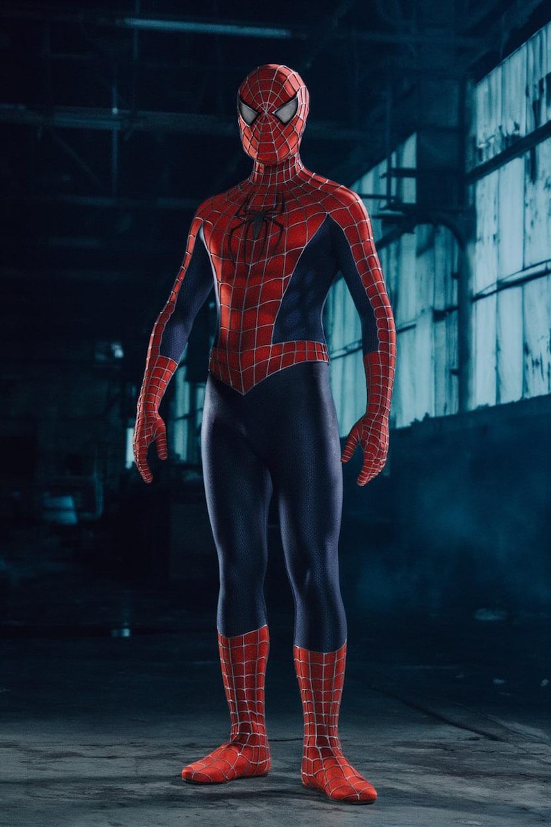 May include: A full-body shot of a person in a Spider-Man costume. The costume is red with a black spider emblem on the chest and a web pattern. The mask covers the entire head, and the background is a dark industrial setting.